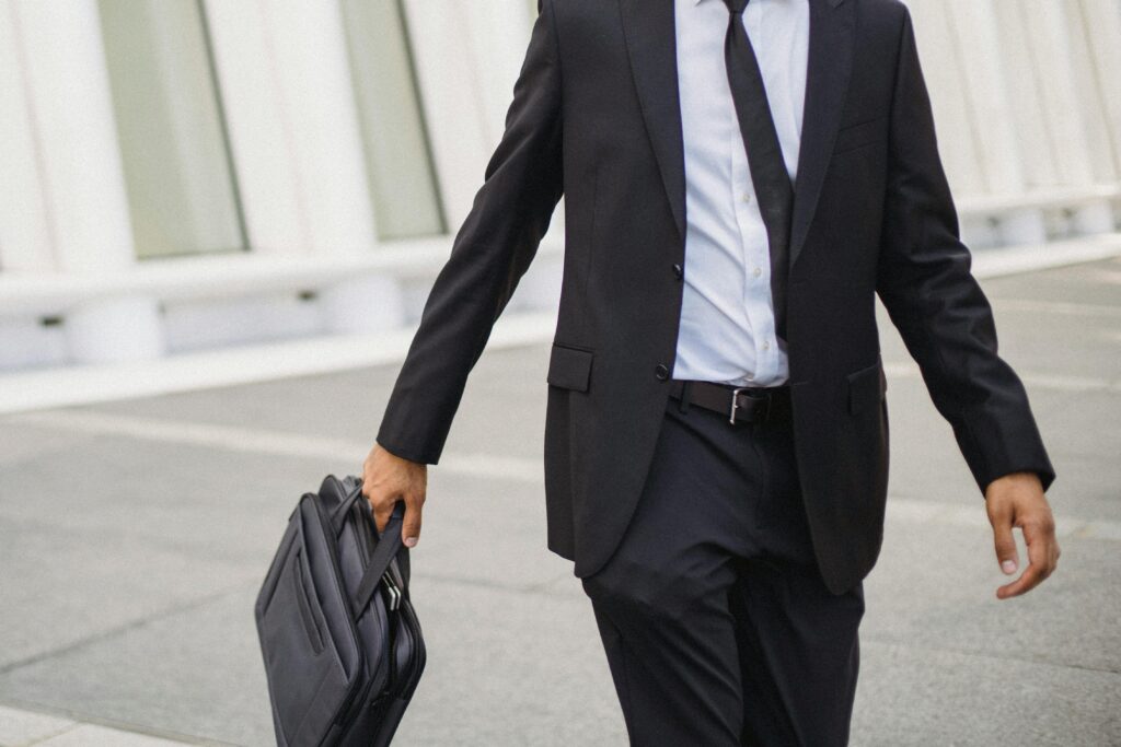 An image showing a person walking down a street in a suit holding a briefcase