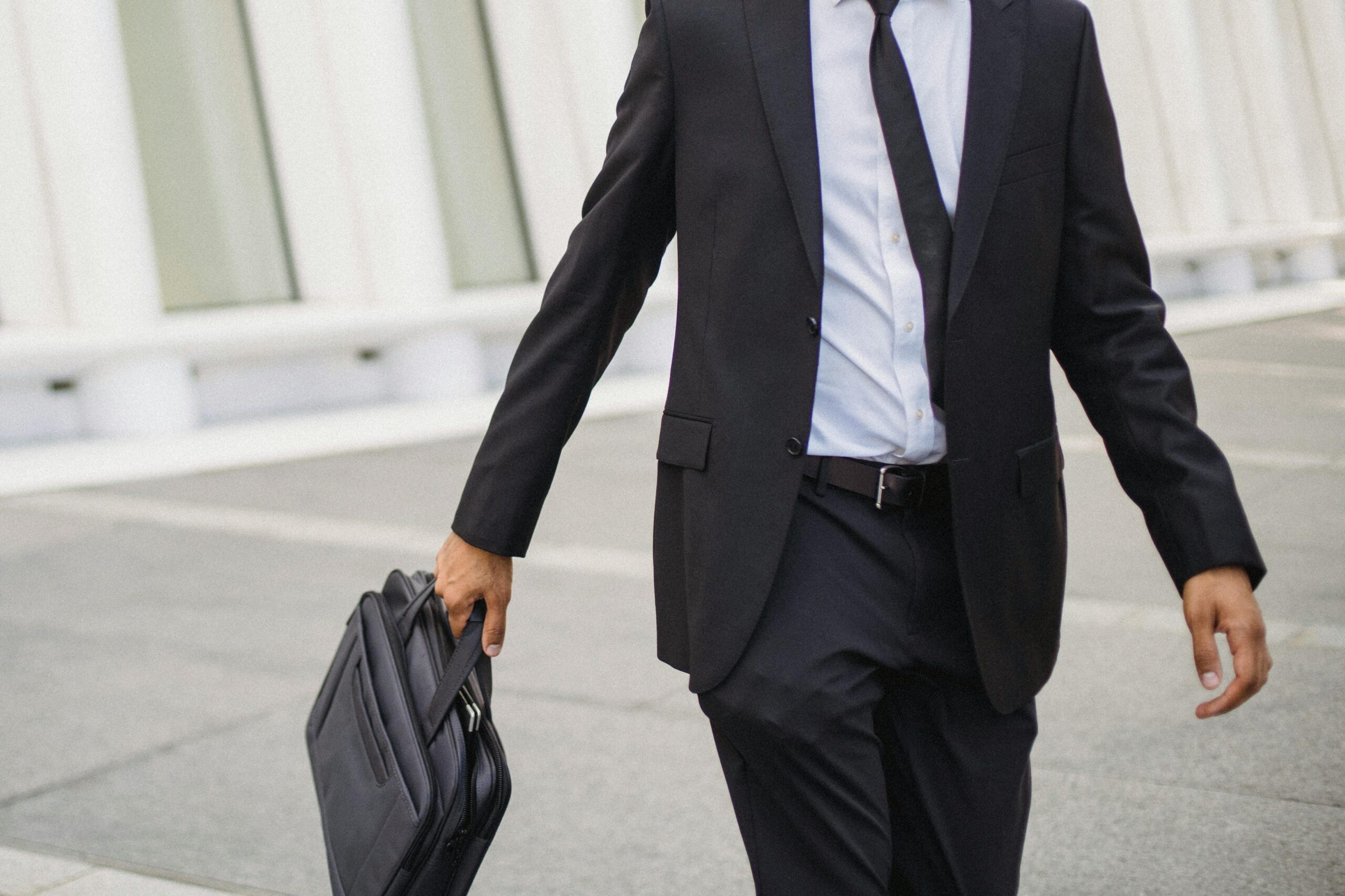 An image showing a person walking down a street in a suit holding a briefcase