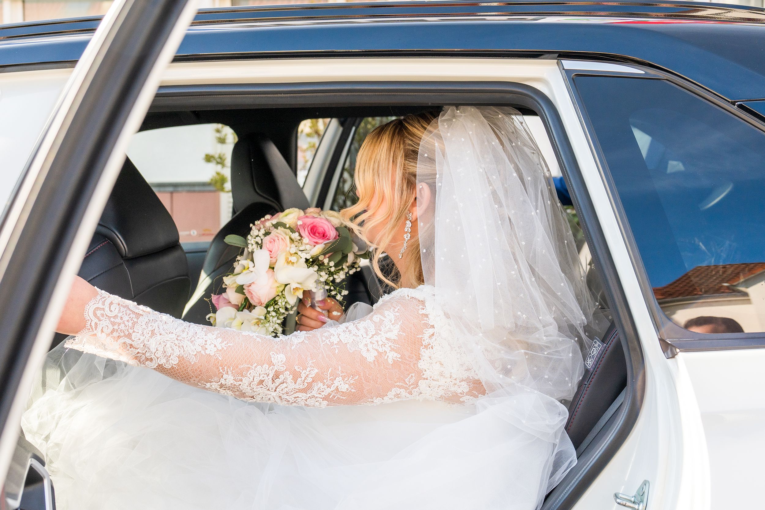 An image showing a bride in a luxury wedding car by a premium wedding chauffeur